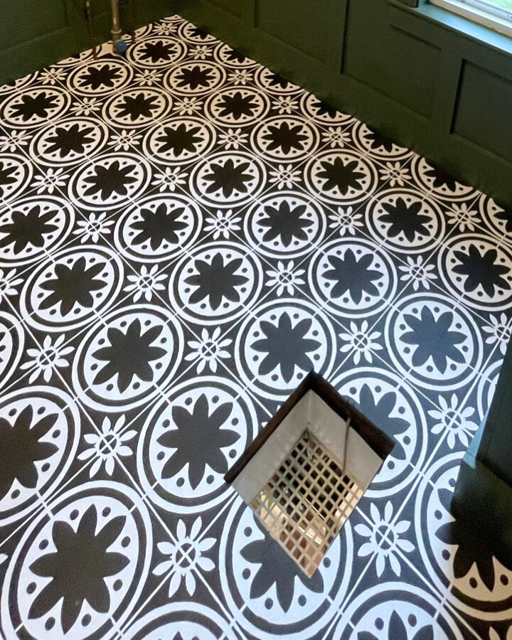 close-up-image-of-stenciled-black-and-white-hardwood-flooring-in-a-green-bathroom-with-board-and-batten