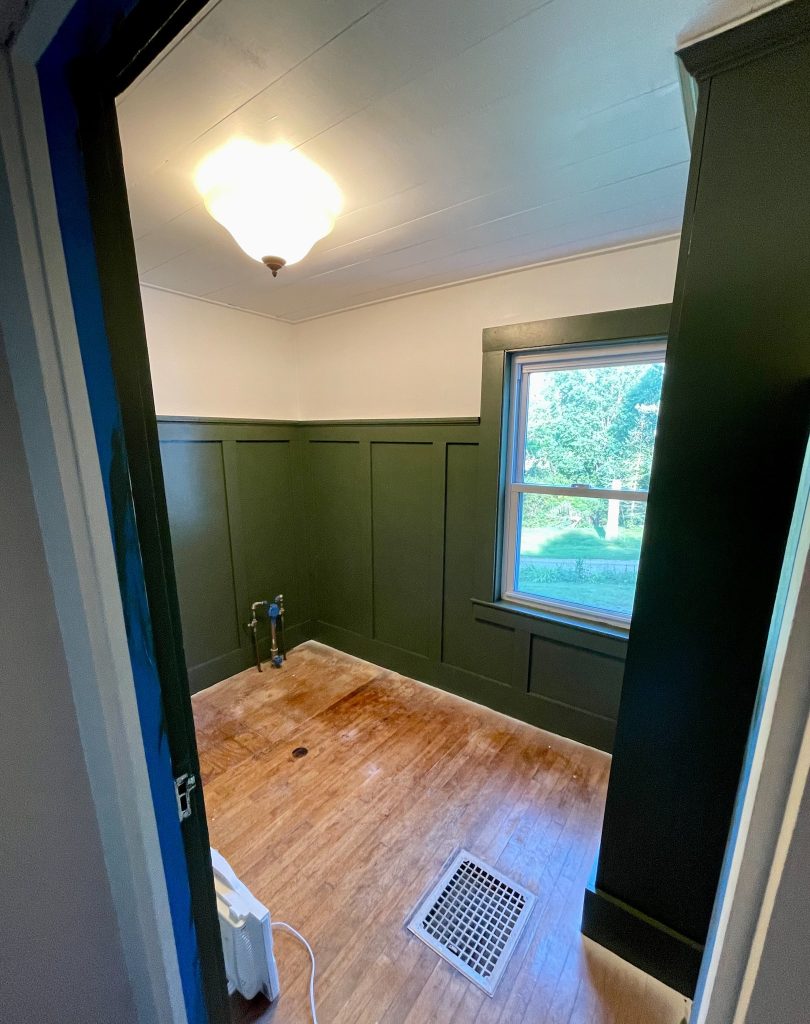 Completed DIY board and batten walls in dark green with wood floor farmhouse bathroom